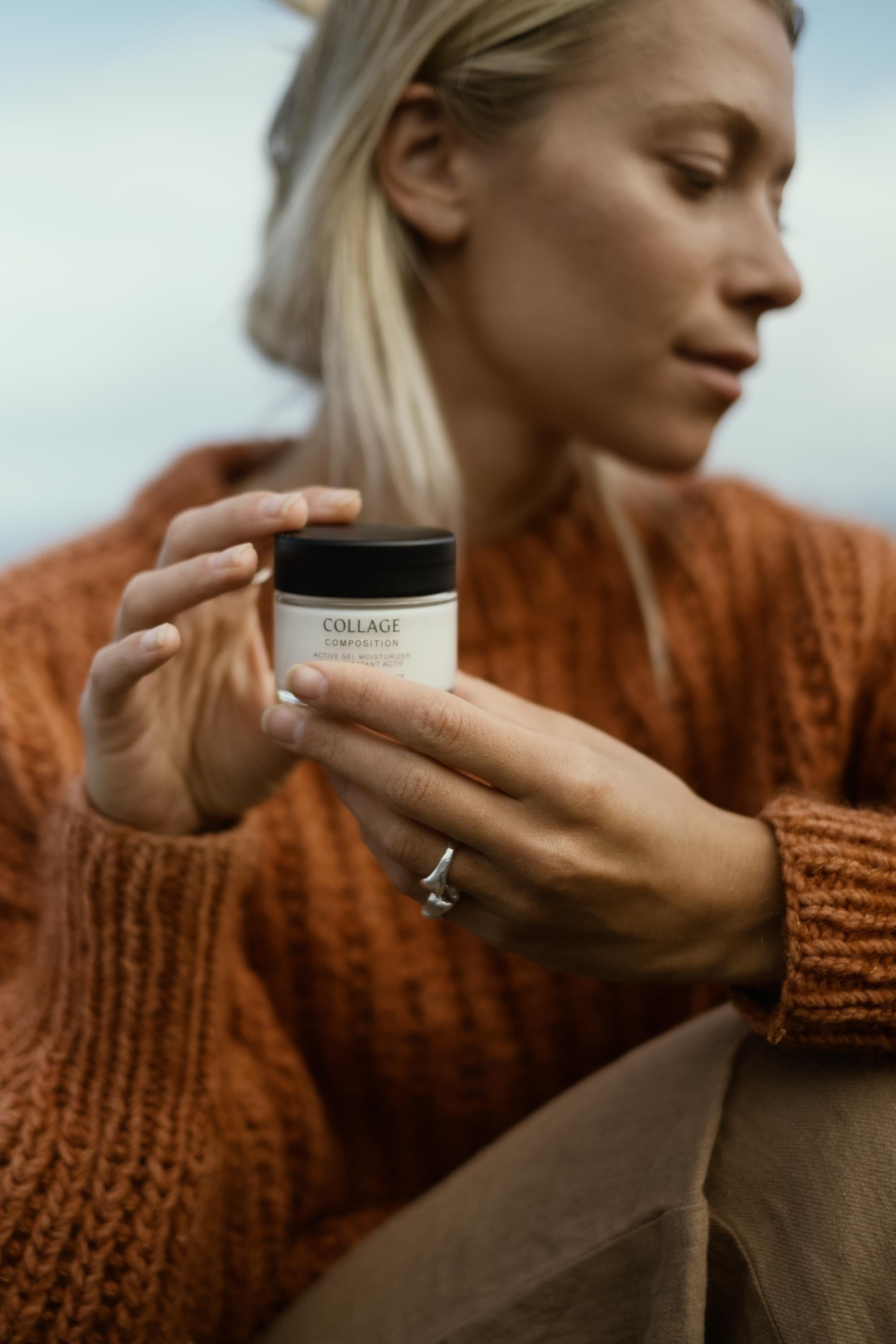 Woman holding a jar of Collage Cream with a blurred background
