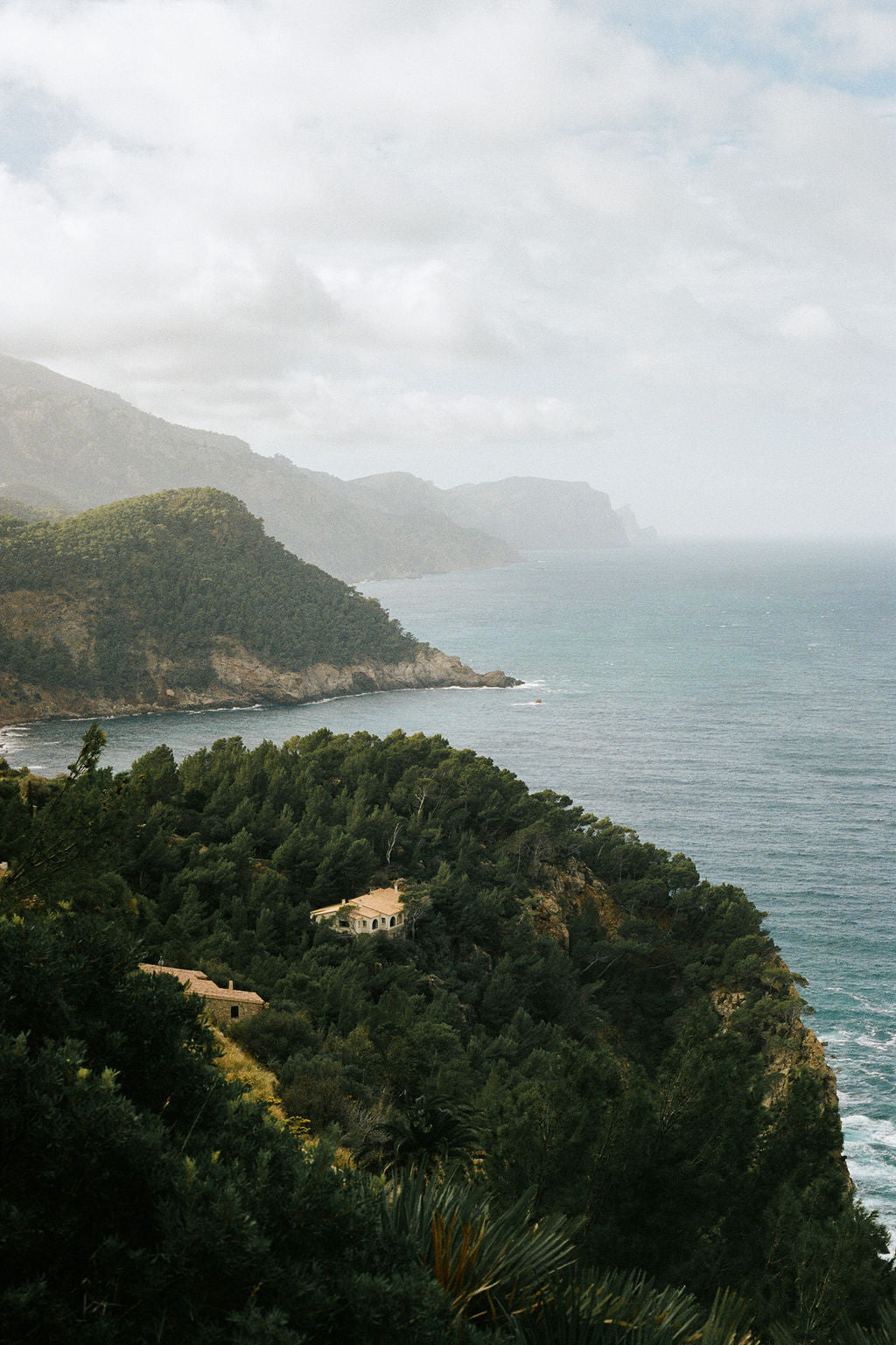 Scenic view of a coastal landscape in British Columbia with greenery and a house on a cliff.